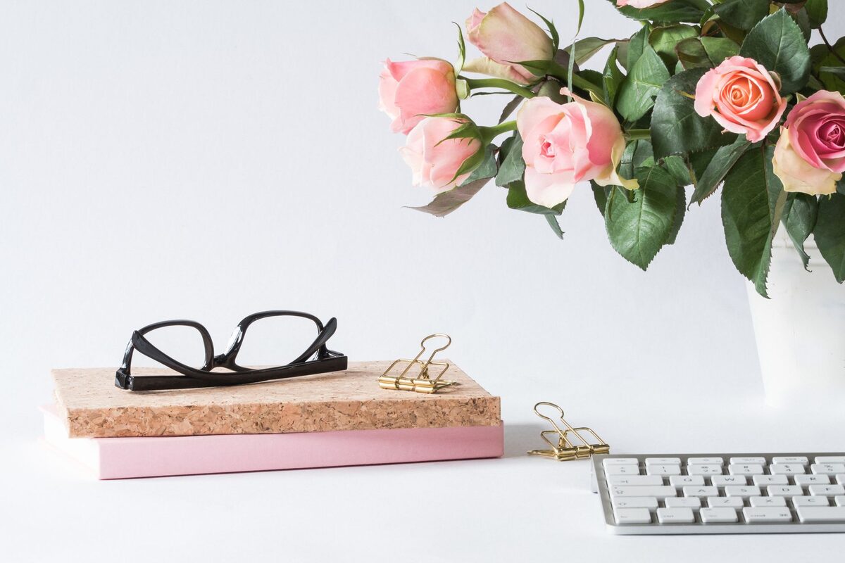 Escritorio de oficina con un jarrón de rosas junto al teclado