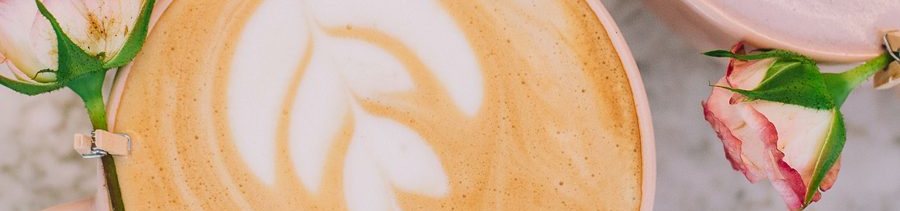 Latte con arte latte y rosas sobre mesa de mármol