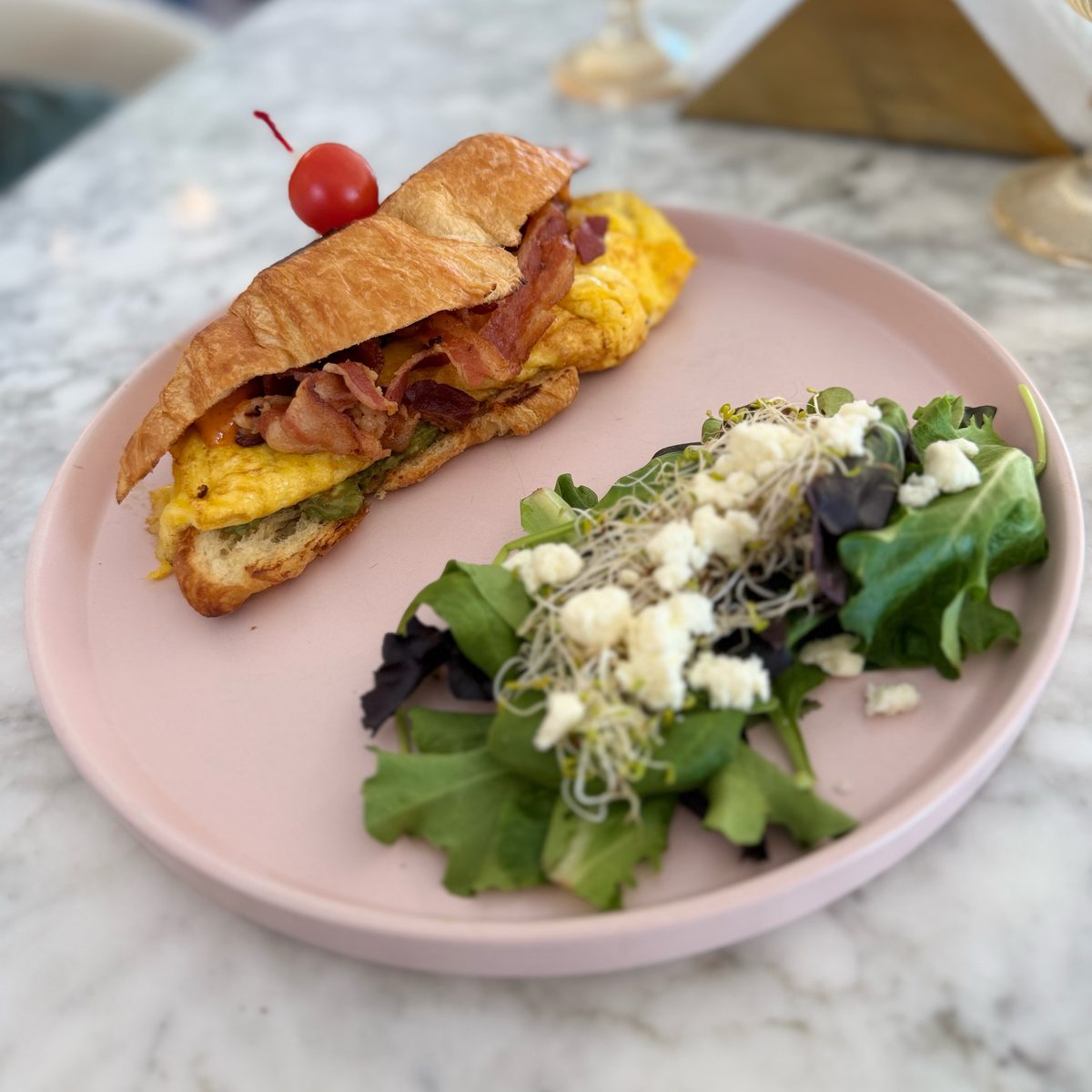 Croissant con huevo y tocino, con ensalada